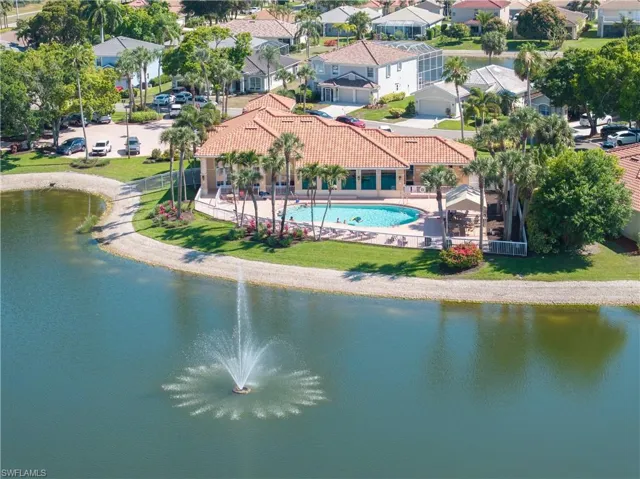Aerial perspective of suburban area featuring a pool and a nearby body of water