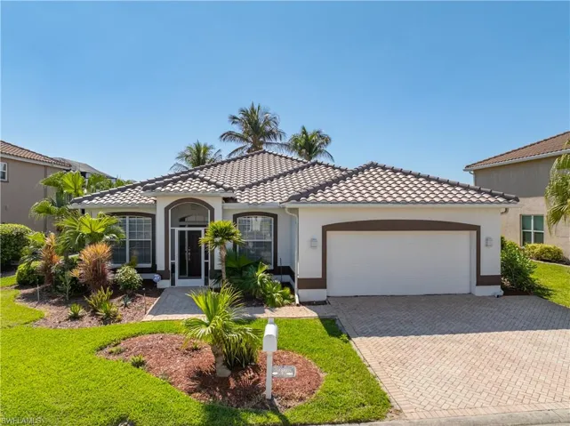 Mediterranean / spanish home with an attached garage, decorative driveway, stucco siding, a tiled roof, and a front yard