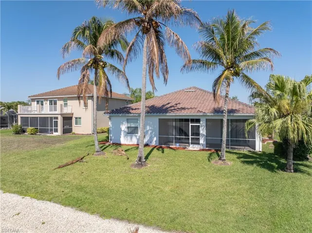 Rear view of property featuring a sunroom, a lawn, and stucco siding