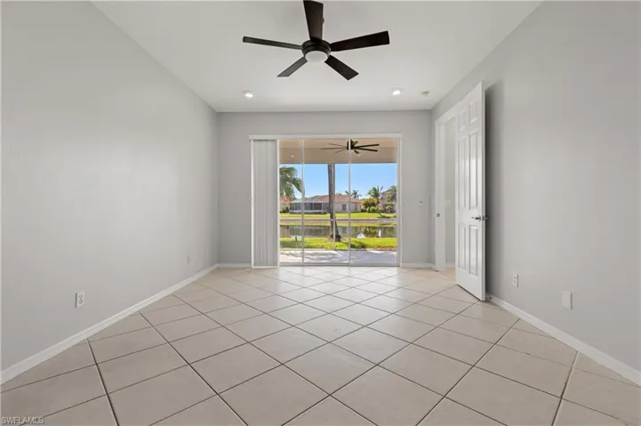 Empty room featuring ceiling fan, light tile patterned flooring, and a water view