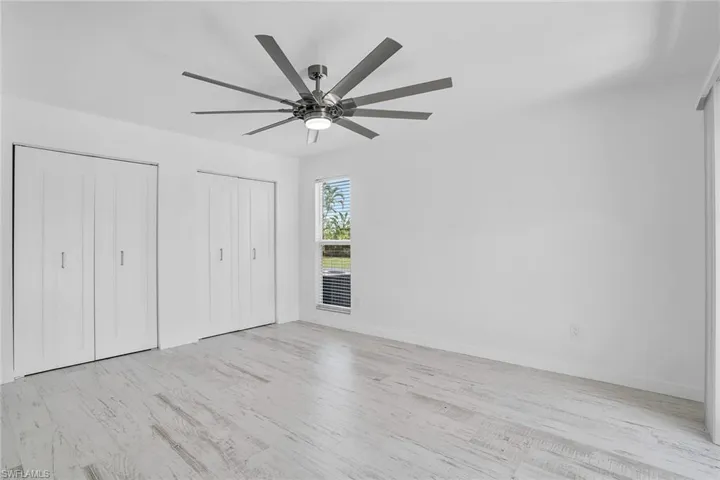 Unfurnished bedroom featuring ceiling fan, light hardwood / wood-style floors, and multiple closets