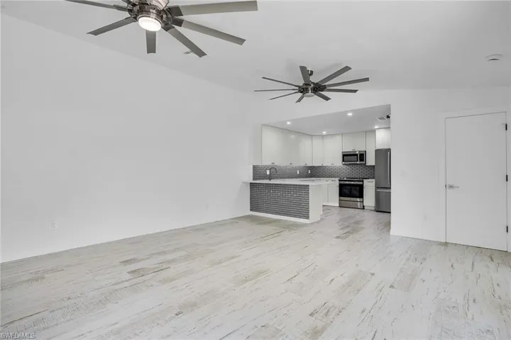 Unfurnished living room with ceiling fan, light wood-type flooring, and sink