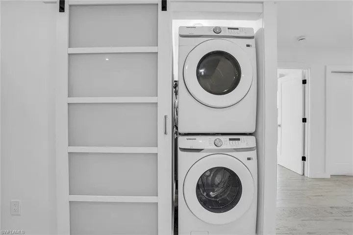 Laundry room featuring stacked washer / dryer, hardwood / wood-style floors, and a barn door