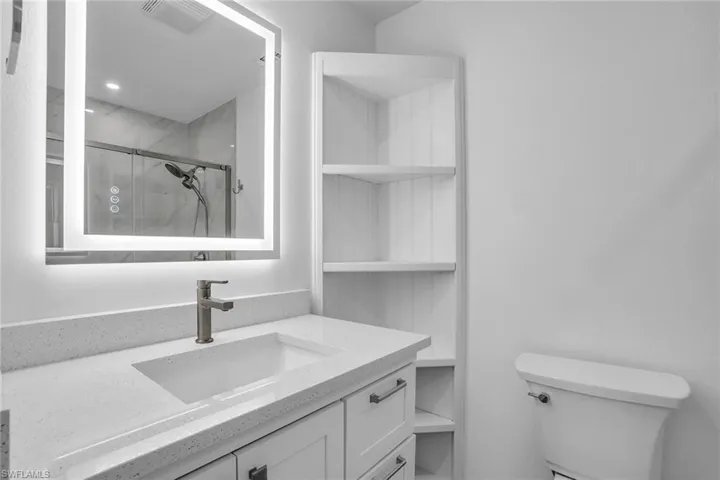 Bathroom featuring an enclosed shower, vanity, and toilet