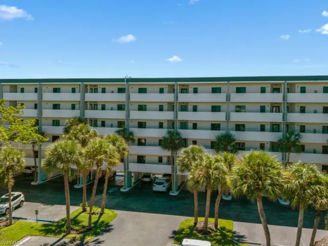 View of apartment building / complex featuring covered parking