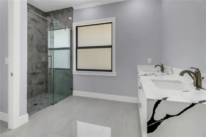 Bathroom featuring dual vanity, an enclosed shower, and tile patterned flooring