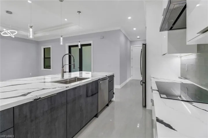 Kitchen with a tray ceiling, pendant lighting, sink, light stone counters, and light tile patterned floors