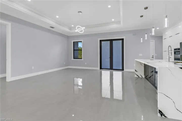 Unfurnished living room with tile patterned floors and a tray ceiling