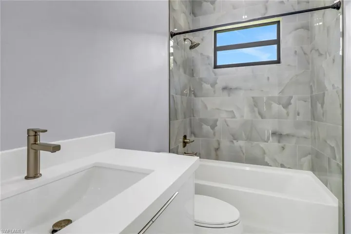 Full bathroom featuring vanity, tiled shower / bath, and toilet