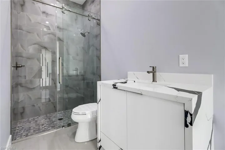 Bathroom featuring vanity, a shower with door, and toilet