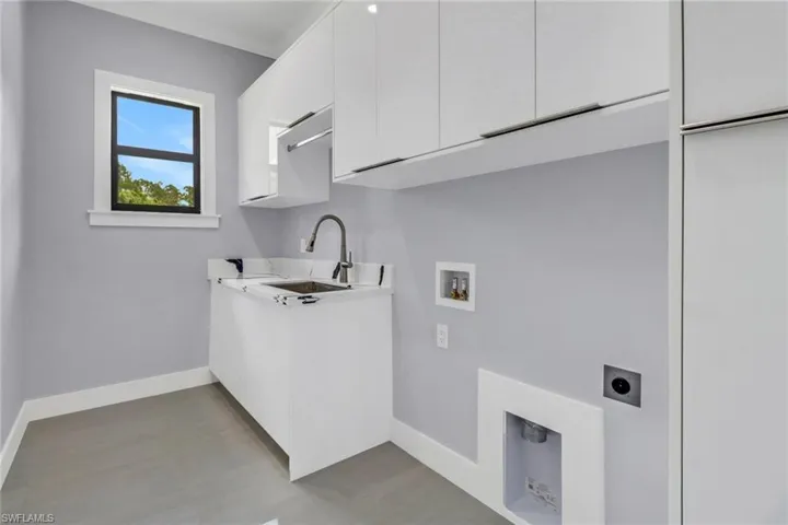 Clothes washing area with hardwood / wood-style flooring, sink, electric dryer hookup, cabinets, and hookup for a washing machine