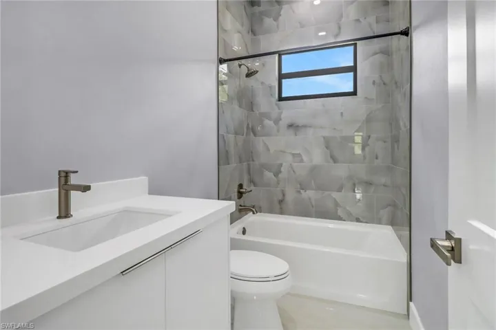 Full bathroom with tiled shower / bath combo, toilet, and vanity