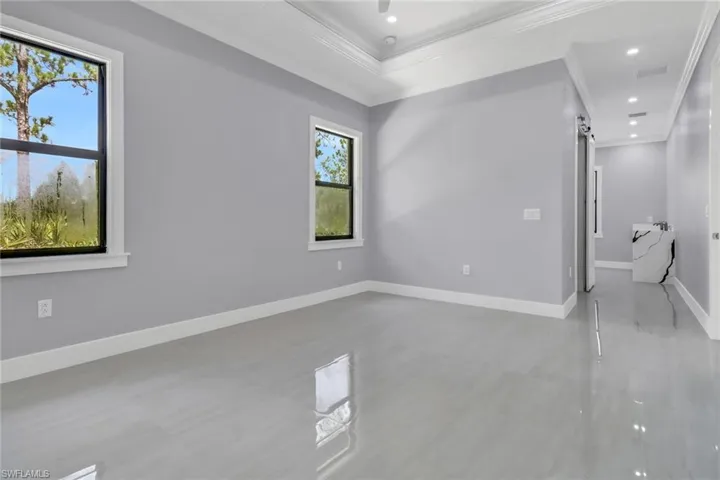 Empty room featuring tile patterned floors, crown molding, and a raised ceiling