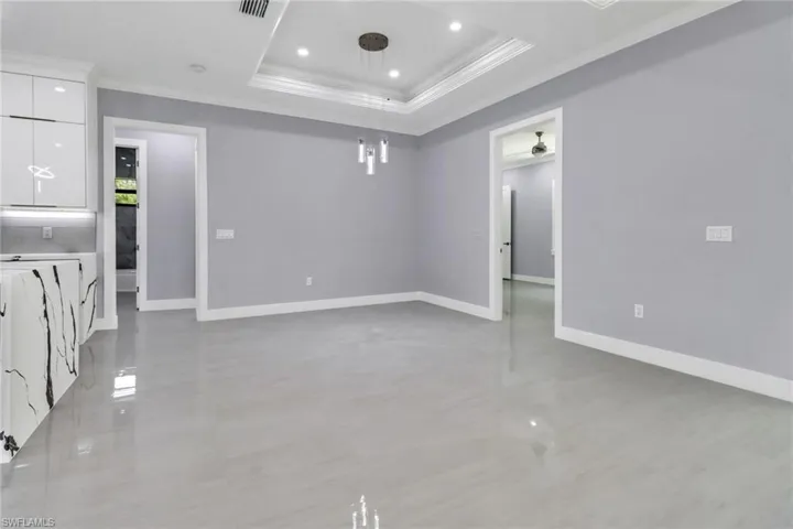 Tiled empty room featuring crown molding and a raised ceiling