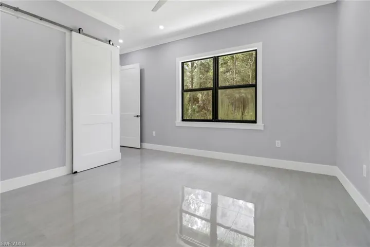 Unfurnished room with light tile patterned flooring, a barn door, and ornamental molding