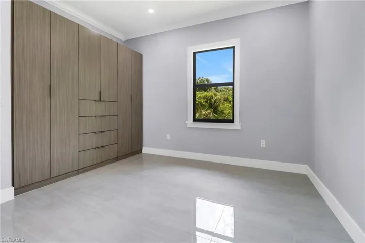 Unfurnished bedroom with light tile patterned floors and ornamental molding