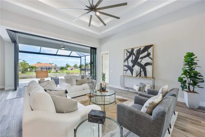 Living room featuring a tray ceiling, ceiling fan, and light hardwood / wood-style flooring