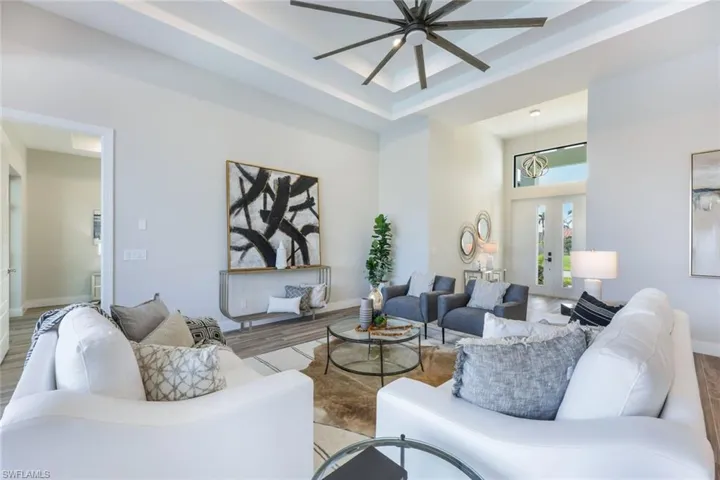 Living room with ceiling fan, a raised ceiling, and hardwood / wood-style flooring
