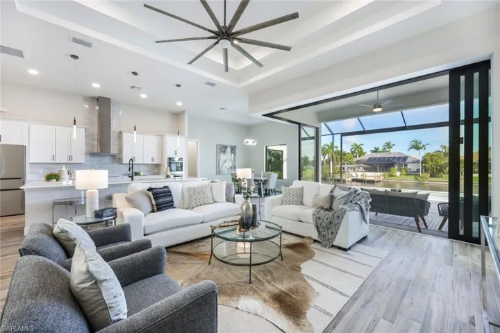 Living room featuring light hardwood / wood-style floors, ceiling fan, and a raised ceiling