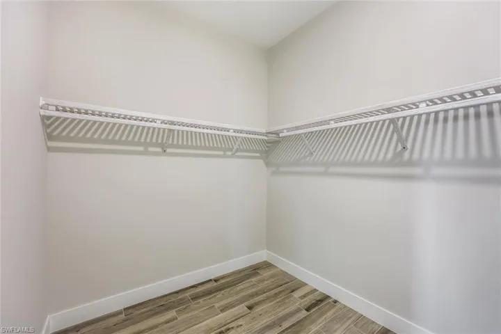 Walk in closet with hardwood / wood-style floors