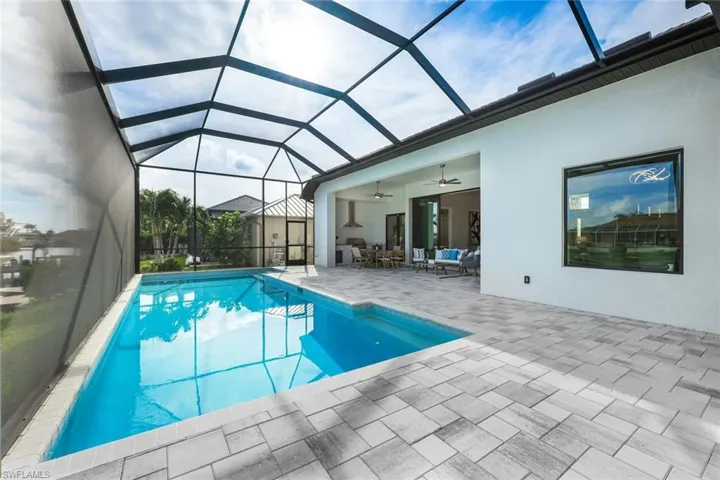 View of swimming pool featuring ceiling fan, glass enclosure, and a patio