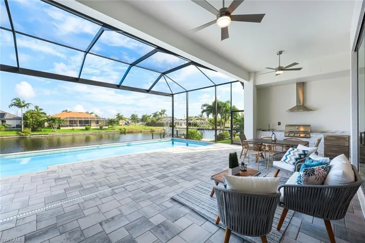 View of pool featuring a water view, a lanai, grilling area, ceiling fan, and a patio area