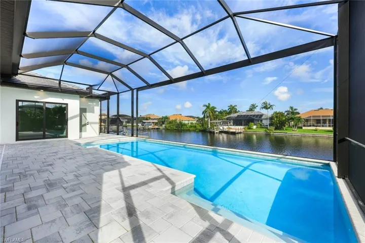 View of swimming pool with glass enclosure, a water view, and a patio area