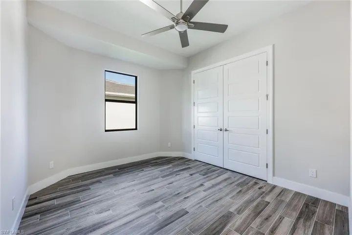 Unfurnished bedroom with wood-type flooring, ceiling fan, and a closet