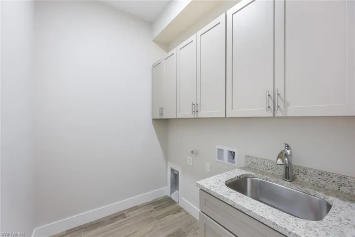 Laundry room featuring hookup for a washing machine, sink, light hardwood / wood-style flooring, and cabinets