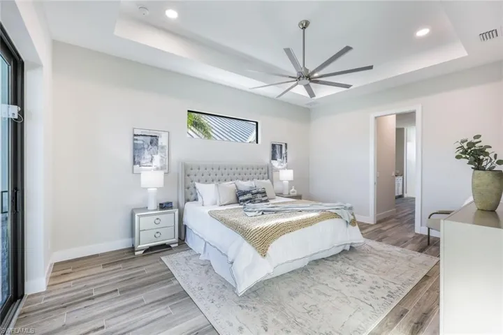 Bedroom featuring light wood-type flooring, a tray ceiling, and ceiling fan