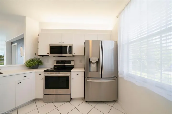 Kitchen with appliances with stainless steel finishes, white cabinets, light countertops, and light tile patterned flooring