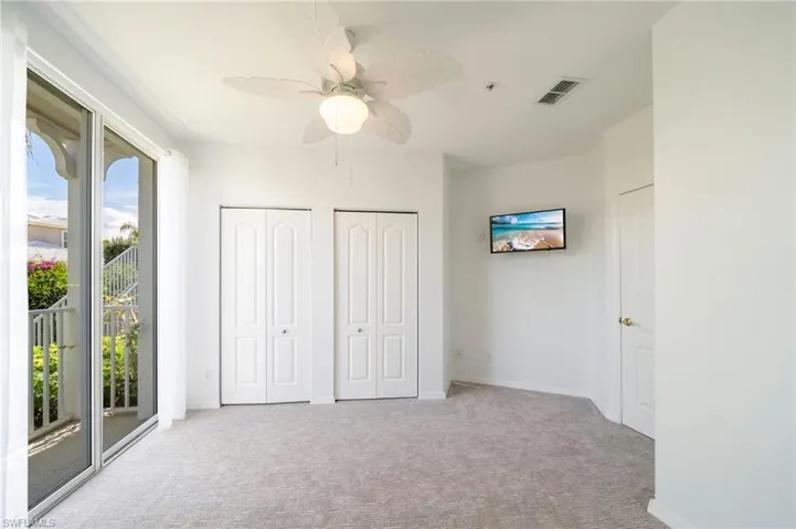 Unfurnished bedroom featuring two closets, access to exterior, light carpet, and a ceiling fan