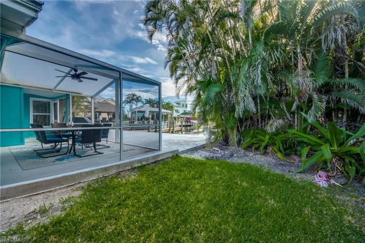 View of grassy yard featuring a lanai, a sunroom, ceiling fan, and a patio area