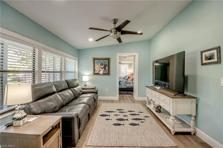 Living area with vaulted ceiling, light wood-type flooring, a ceiling fan, and recessed lighting