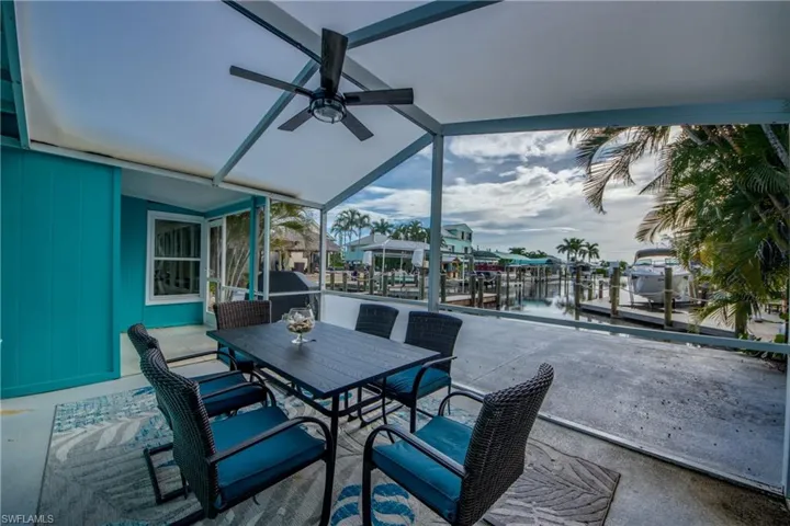 View of patio / terrace with a ceiling fan, a water view, outdoor dining space, and a lanai