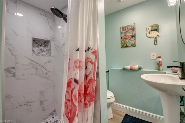 Bathroom with a marble finish shower and wood finished floors
