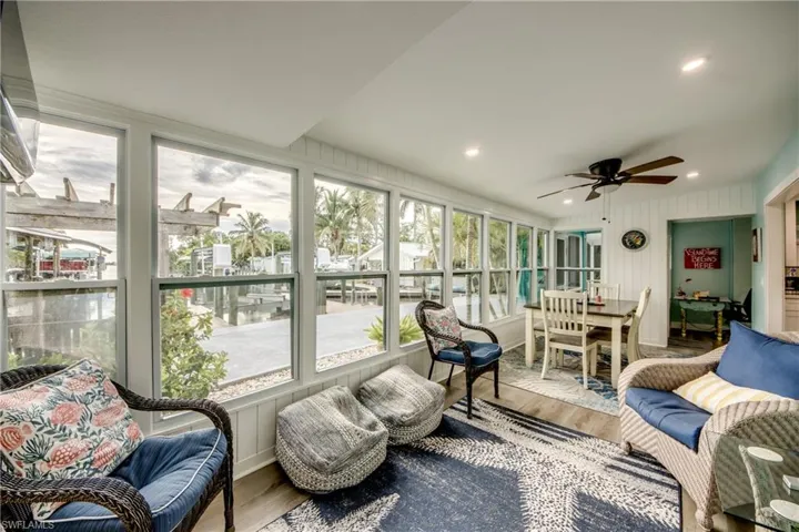 Sunroom / solarium with wood finished floors, recessed lighting, ceiling fan, outdoor dining area, and wooden walls