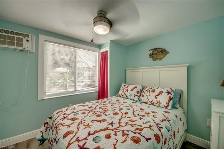 Bedroom featuring wood finished floors, a ceiling fan, and a wall mounted air conditioner