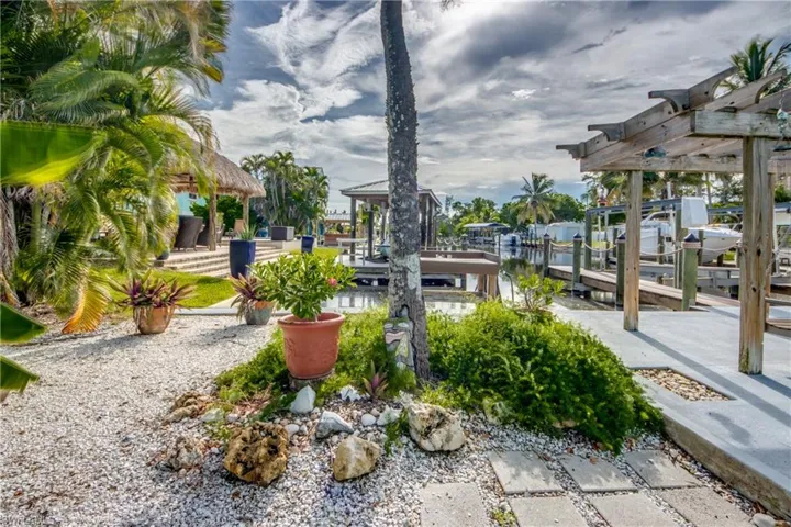 View of yard with a dock, a water view, boat lift, and a patio