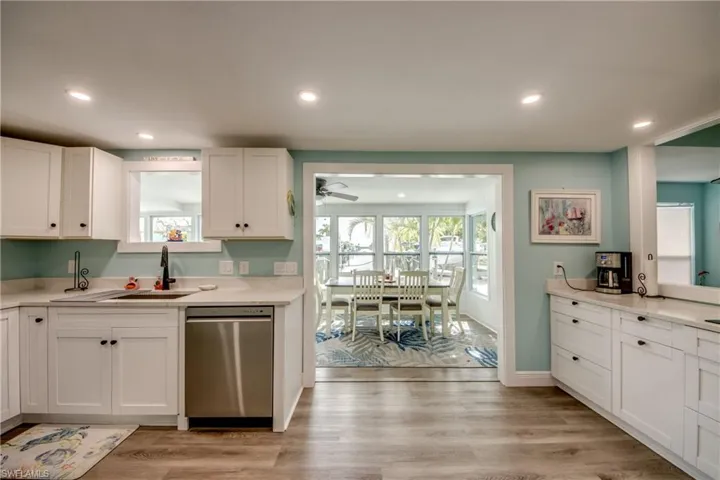 Kitchen featuring stainless steel dishwasher, white cabinets, recessed lighting, light wood finished floors, and light stone countertops