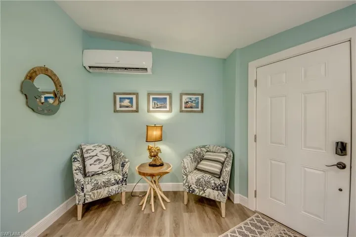 Living area with wood finished floors and a wall mounted AC