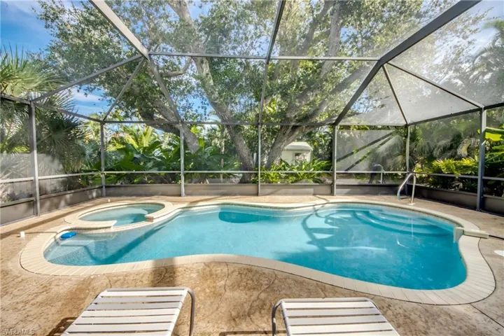 View of pool with a sunroom, a pool with connected hot tub, and glass enclosure
