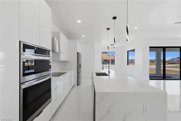 Kitchen with stainless steel appliances, white cabinets, modern cabinets, an island with sink, and hanging light fixtures