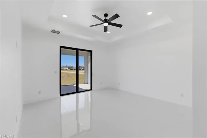 Unfurnished room featuring a tray ceiling, ceiling fan, recessed lighting, and light marble finish flooring