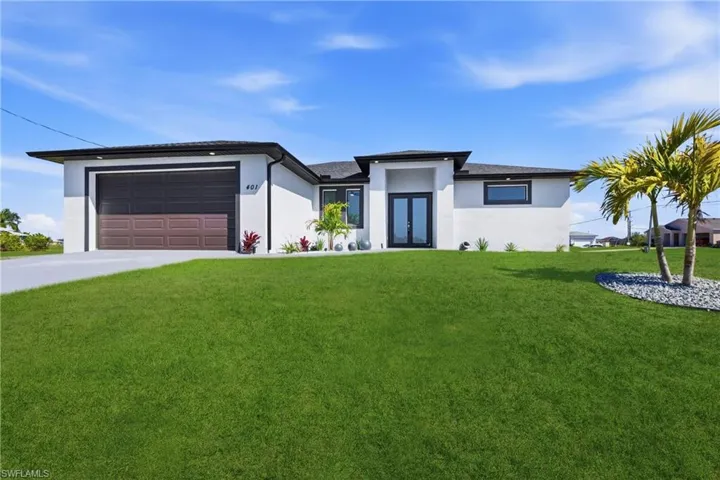 Prairie-style home featuring stucco siding, a front lawn, an attached garage, french doors, and driveway