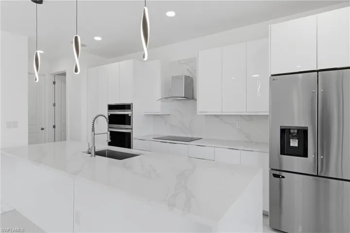 Kitchen featuring white cabinetry, stainless steel appliances, modern cabinets, and light stone countertops