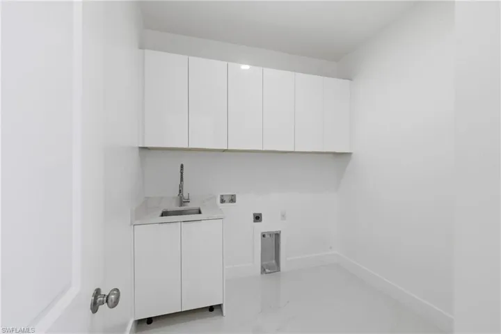 Laundry room featuring electric dryer hookup, light marble finish flooring, cabinet space, and hookup for a washing machine