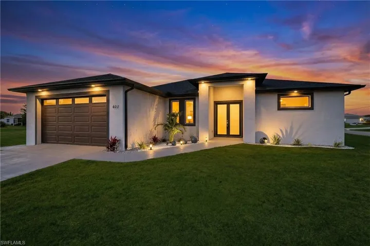 Prairie-style house featuring a front lawn, a garage, concrete driveway, and stucco siding