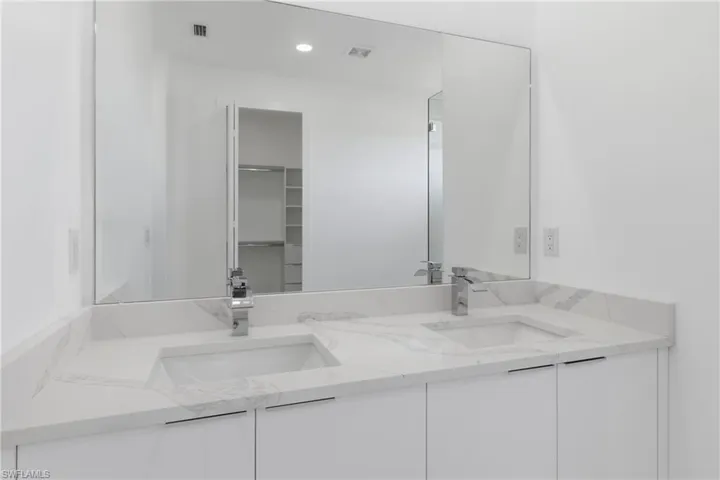 Full bath featuring double vanity, a spacious closet, and recessed lighting