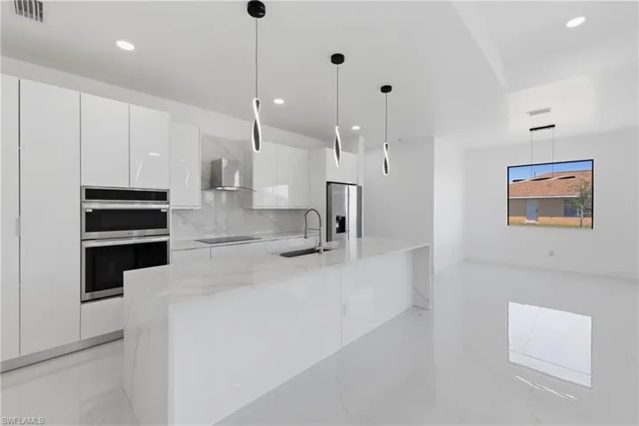 Kitchen featuring white cabinetry, pendant lighting, light stone counters, decorative backsplash, and light marble finish floors